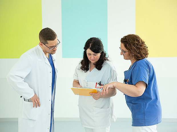 Drei Mitarbeiter bei der Besprechung einer Patientenakte